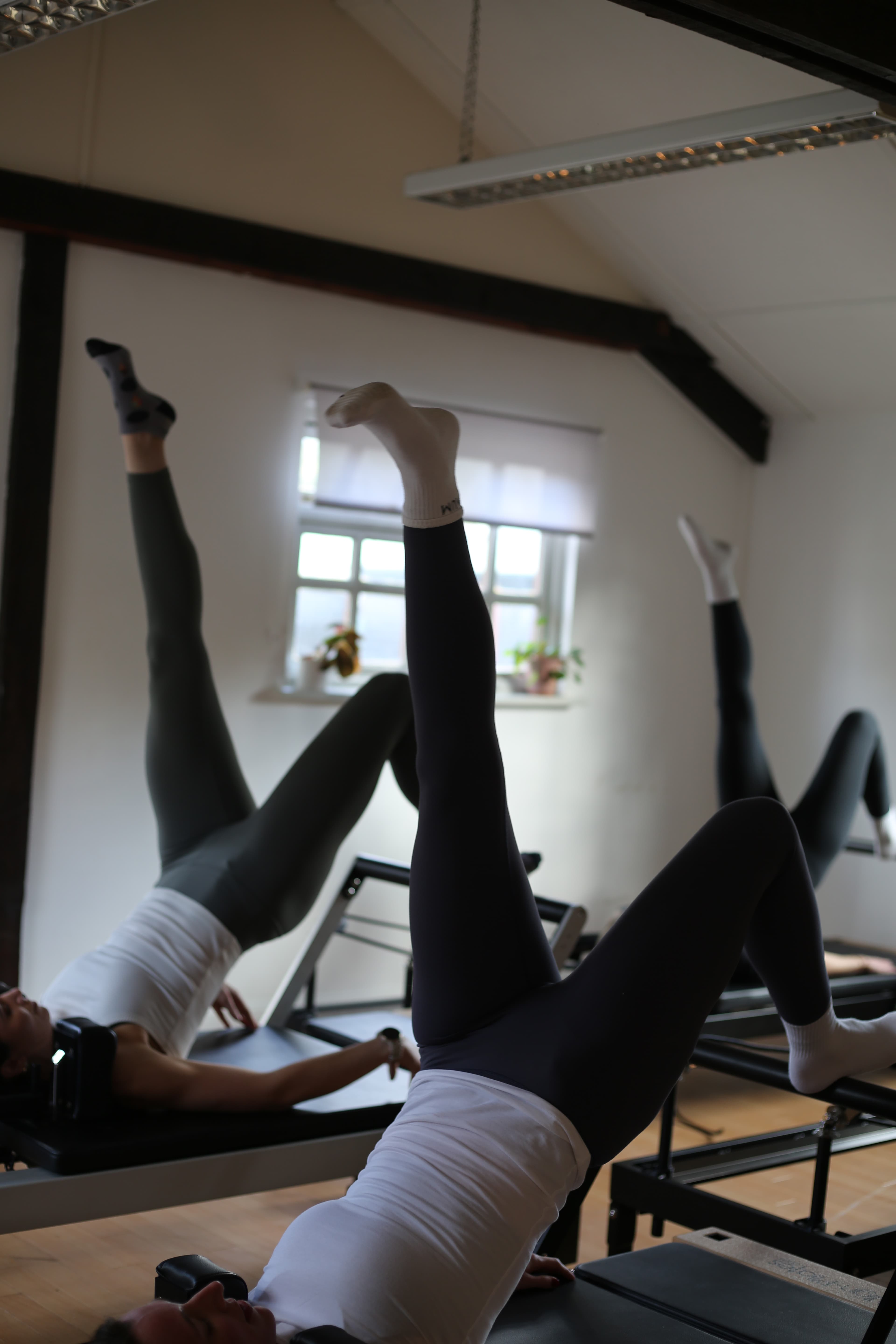 Three members supine on reformers with legs raised