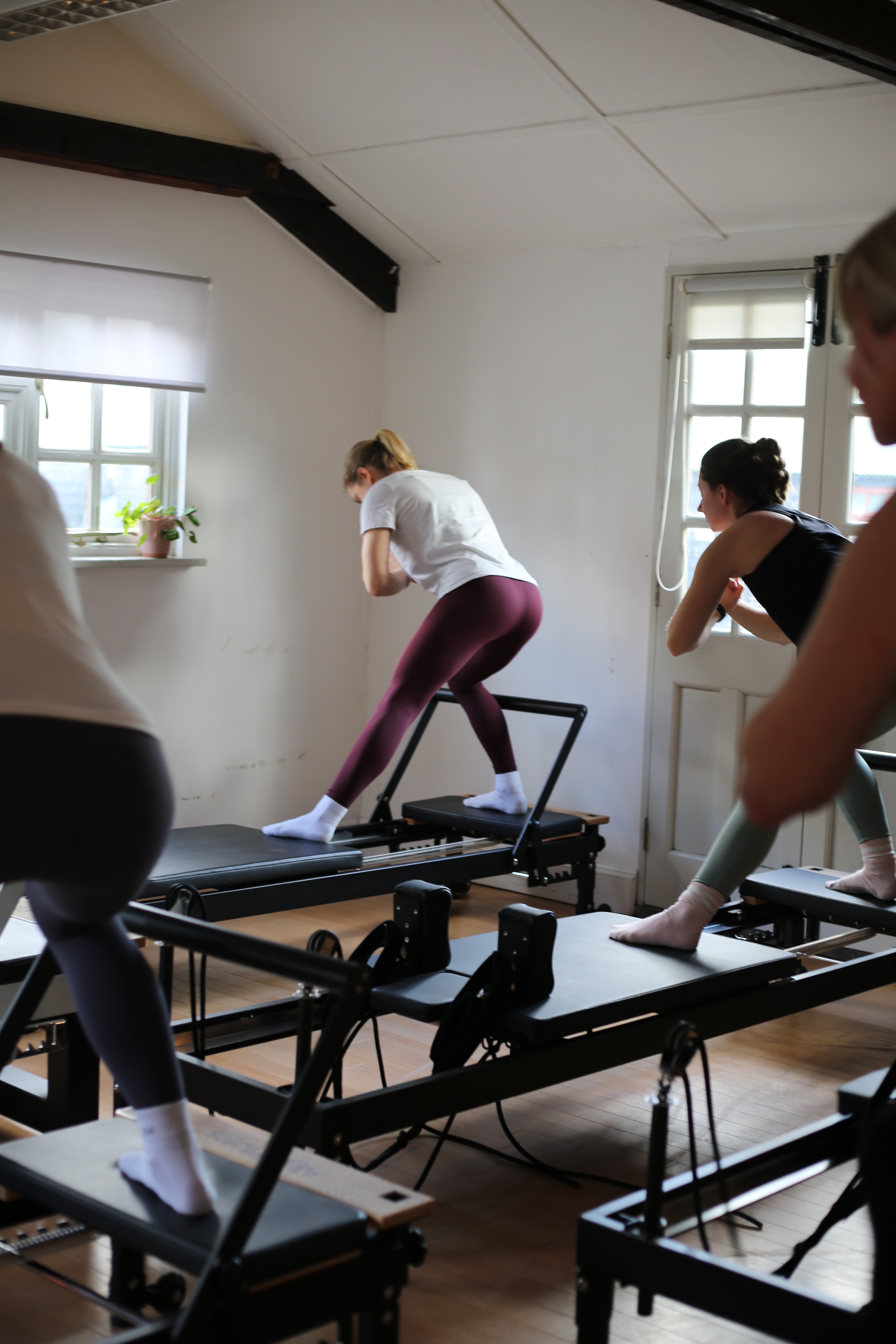 Wide view of a full class, a member mid-lunge standing on a reformer